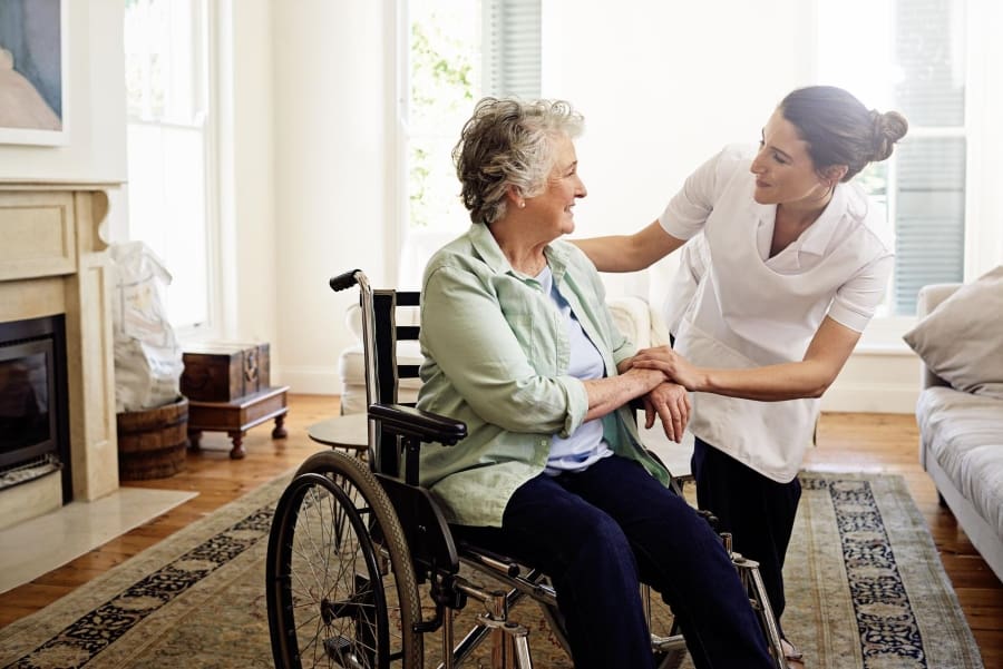 Woman helping elderly in a wheelchair