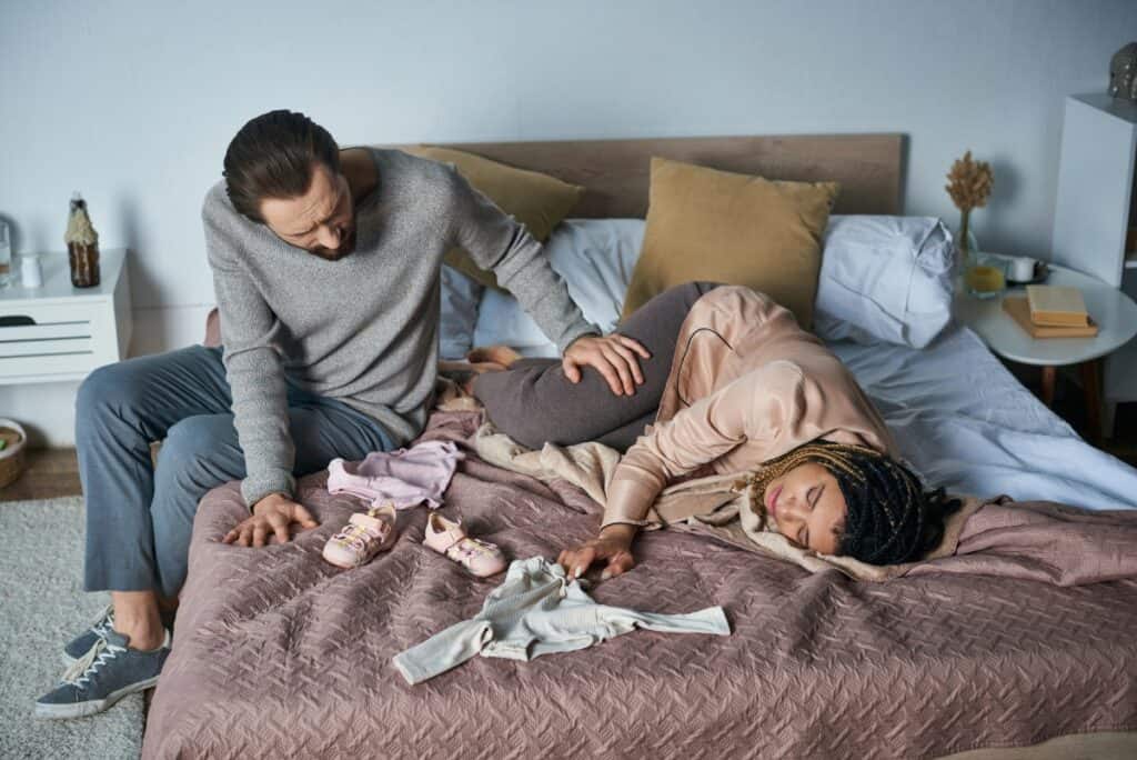 mom and dad on bed crying over baby stuff